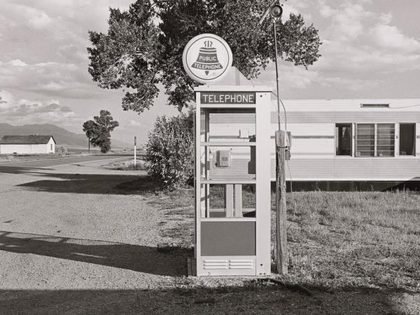 Black and white photo of an old telephone booth in 1970s small town Colorado