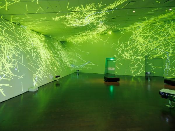 Yellow-green patterns and lights projected into an empty gallery space