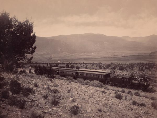 Train running through a landscape in late 1800s Utah