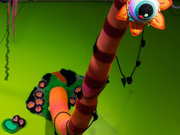 Snake-shaped monster with giant eyeball protruding from the gallery wall