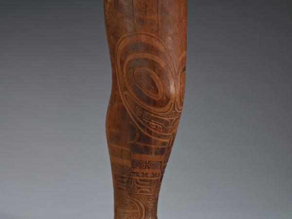 Bust of a leg made out of wood with symbolic patterns meant to resemble tattoos